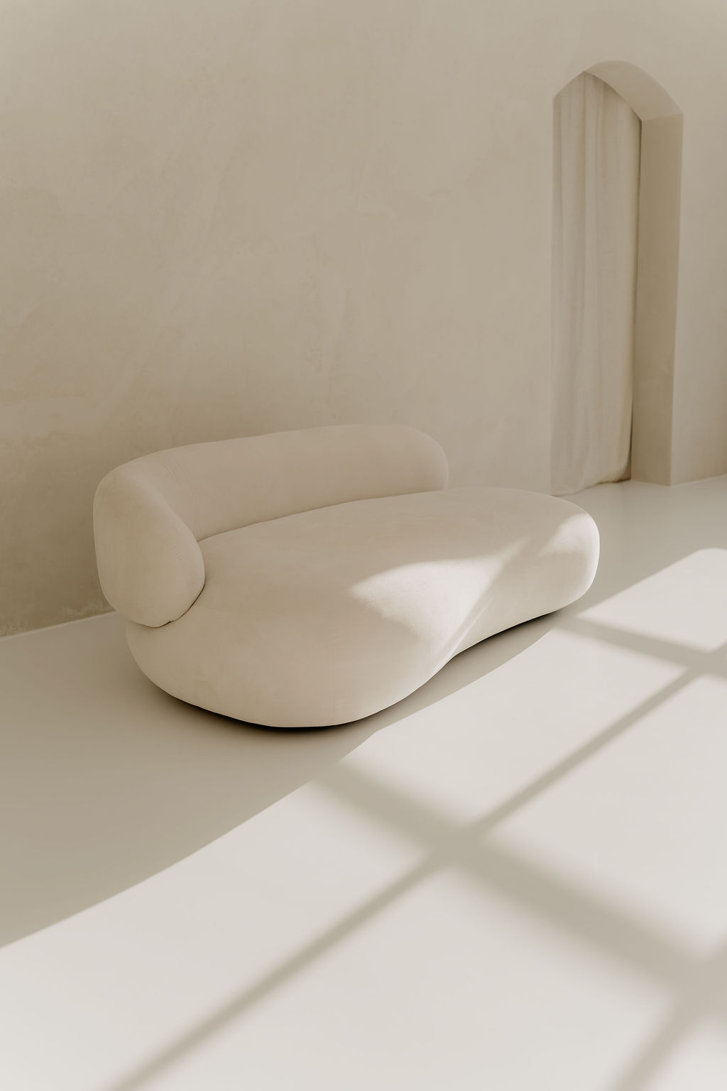 Landloft Tageslichtstudio - modernes Sofa mit Skulpturcharakter und Bogenfenster